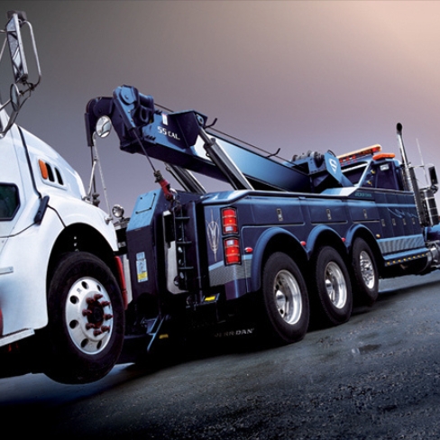 Blue tow truck towing semi truck