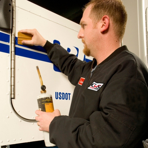 Tech applying vinyl graphics to truck door